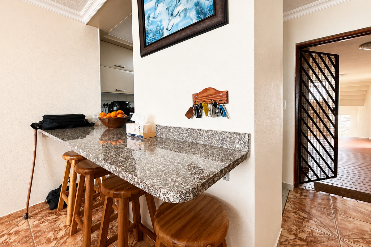 A kitchen breakfast nook featuring a granite countertop, tiled flooring, and a security gate leading to the entrance.