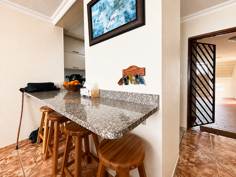 A kitchen breakfast nook featuring a granite countertop, tiled flooring, and a security gate leading to the entrance.