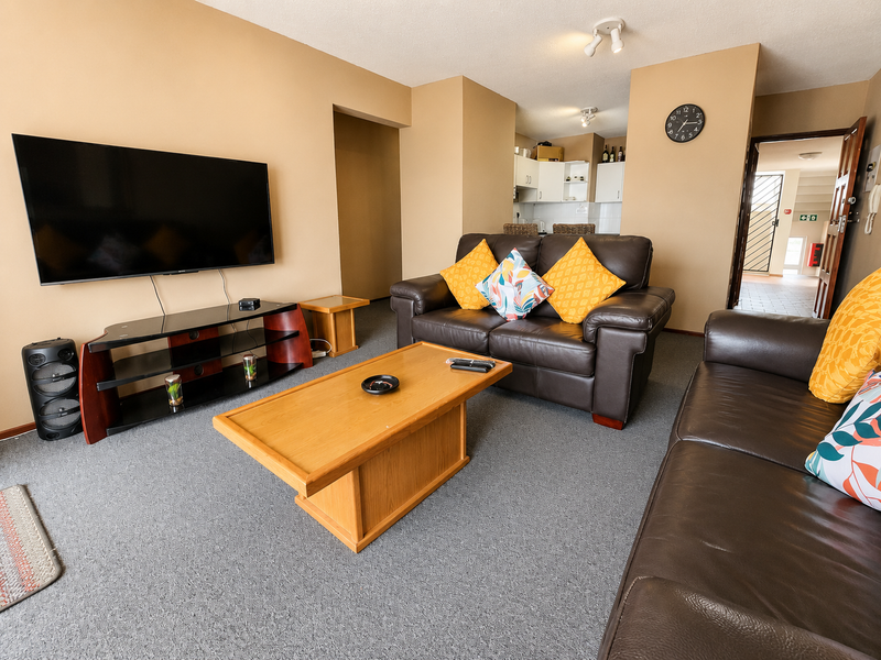 Open-plan living area featuring carpeted flooring and a connected kitchen space, providing a functional layout for daily living.