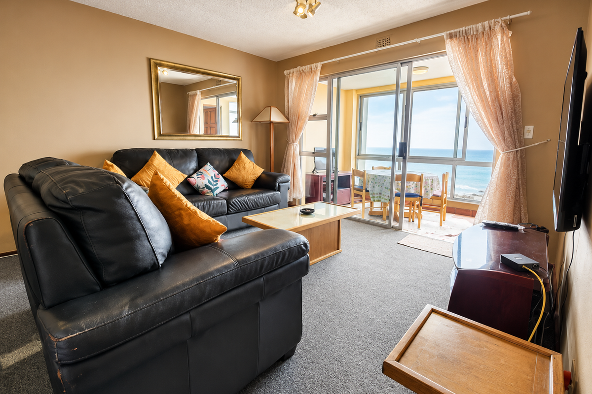 A living room featuring carpet flooring and a sliding glass door leading to a balcony with ocean views.