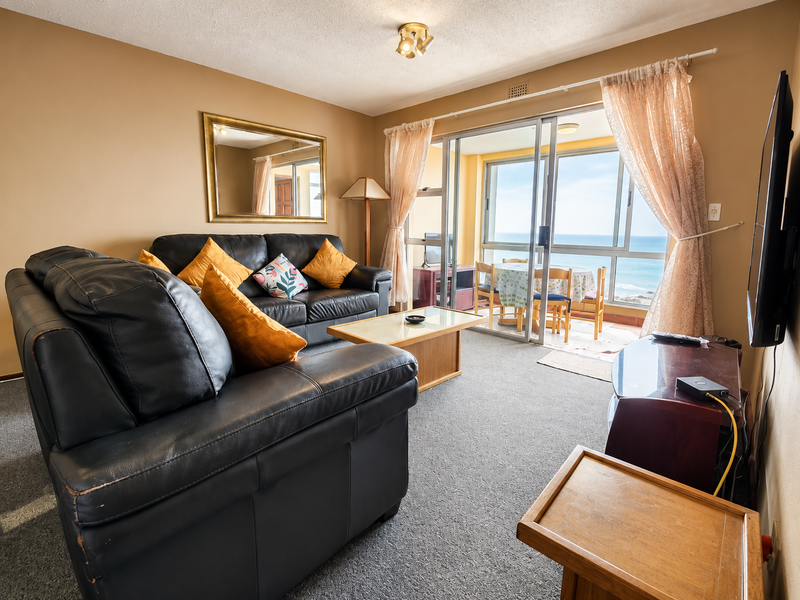 A living room featuring carpet flooring and a sliding glass door leading to a balcony with ocean views.