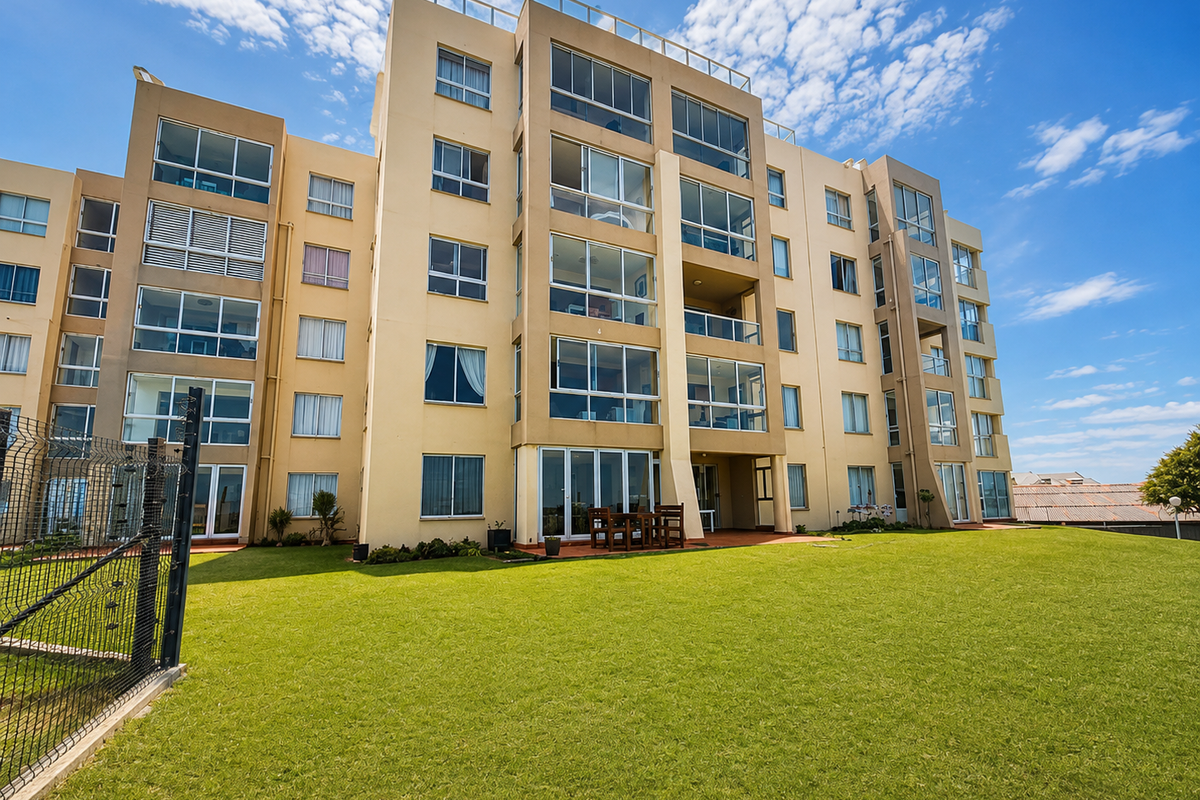A view of the rear elevation of a multi-story apartment building featuring balconies, large windows, and a well-maintained lawn area.