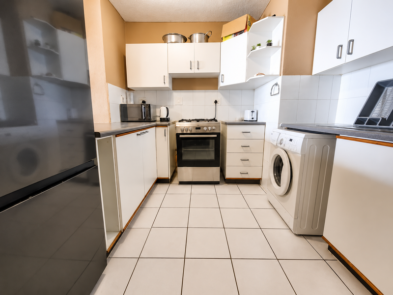 Functional kitchen featuring white cabinetry, gas hob, oven, tiled flooring, and dedicated space for a washing machine.