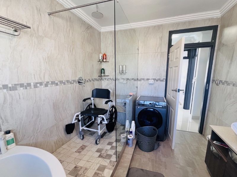 Modern bathroom featuring a spacious walk-in shower with a rainfall shower head, glass screen, and contemporary wall-mounted vanity with a vessel sink.