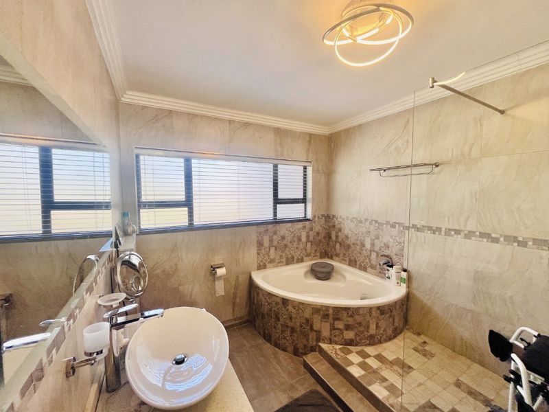 Modern bathroom featuring a corner bathtub, a separate walk-in shower with glass screen, and a stylish vessel sink vanity.