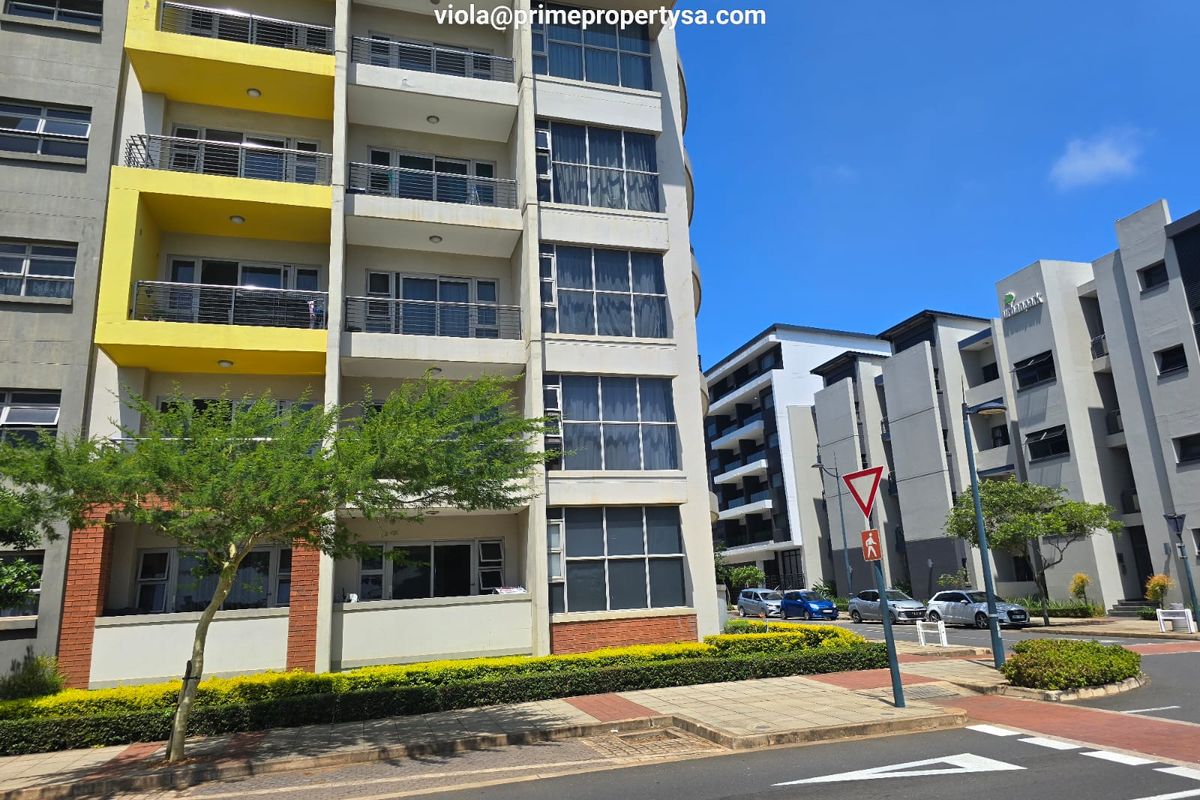 Exterior view of a modern multi-story apartment complex featuring balconies, large windows, and well-maintained surrounding landscaping.