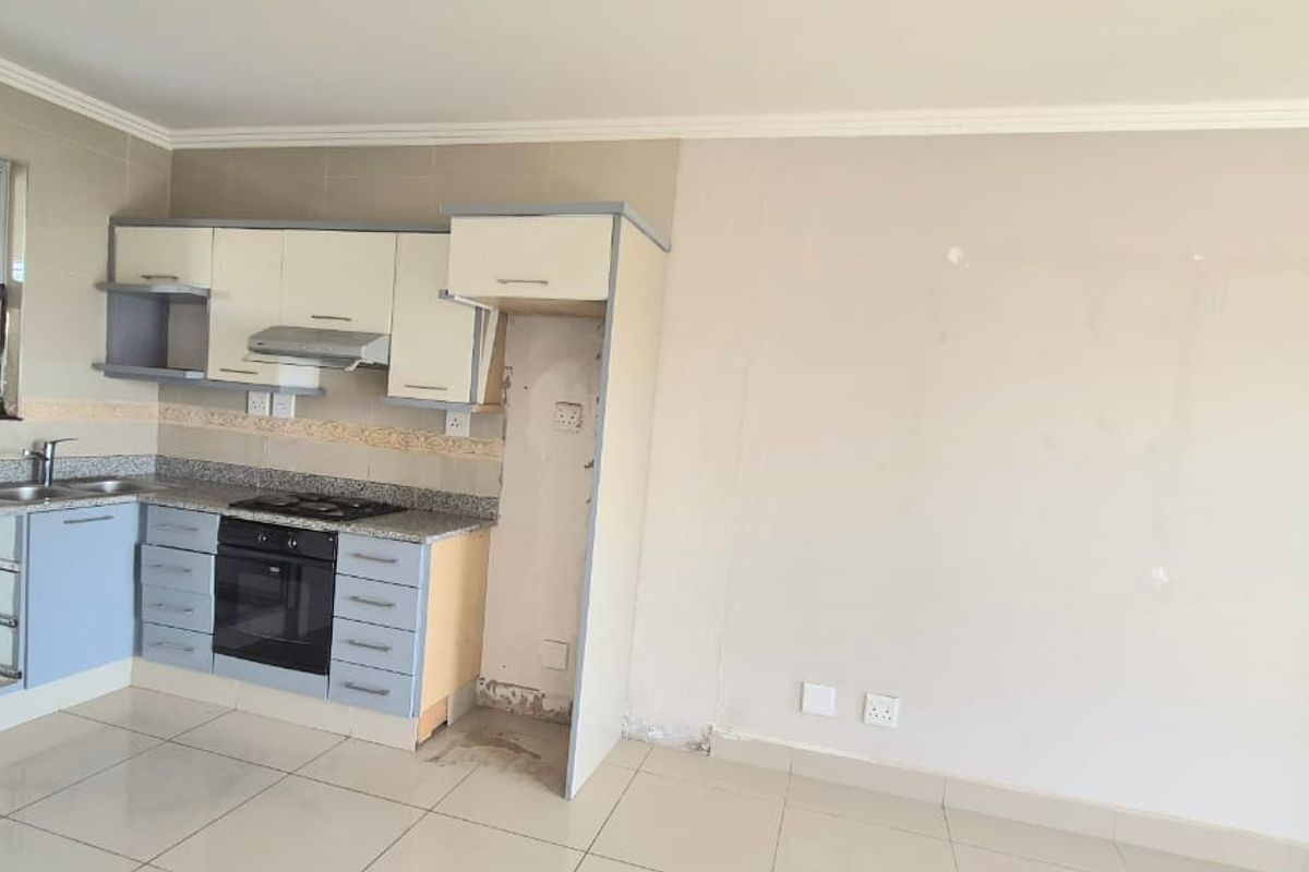 A compact kitchen featuring built-in cabinetry, granite countertops, and integrated appliances, currently requiring minor repairs and cosmetic updates.