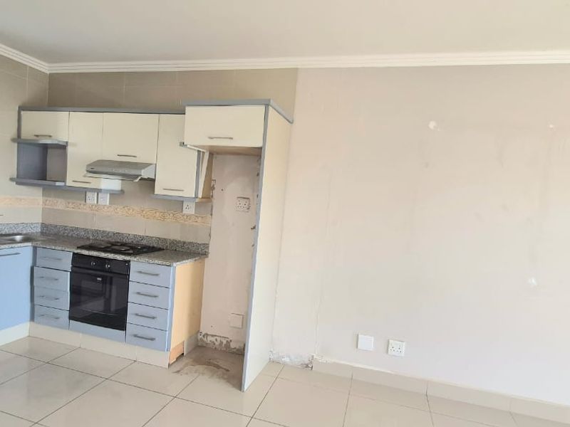A compact kitchen featuring built-in cabinetry, granite countertops, and integrated appliances, currently requiring minor repairs and cosmetic updates.