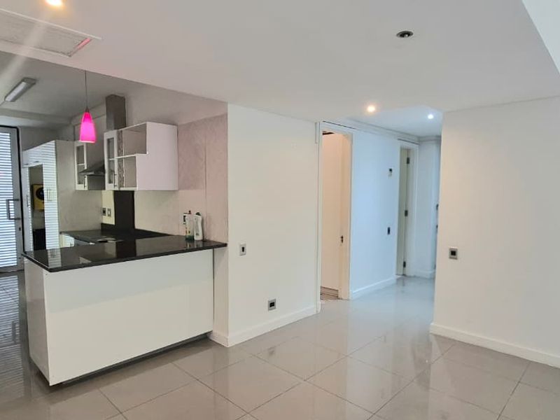 Modern open-plan kitchen and living area featuring sleek cabinetry, granite countertops, and polished tiled flooring throughout.