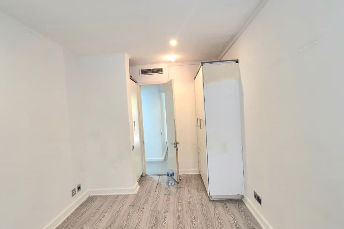 An empty bedroom featuring laminate flooring, recessed lighting, and a built-in wardrobe, presenting a blank canvas for interior design.