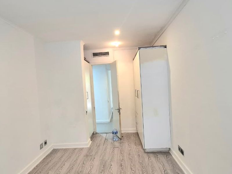 An empty bedroom featuring laminate flooring, recessed lighting, and a built-in wardrobe, presenting a blank canvas for interior design.