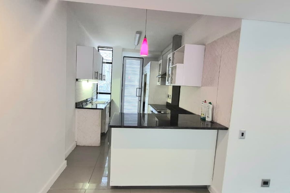 A clean, modern kitchen featuring granite countertops, white cabinetry, and tiled flooring, offering a functional and bright workspace.