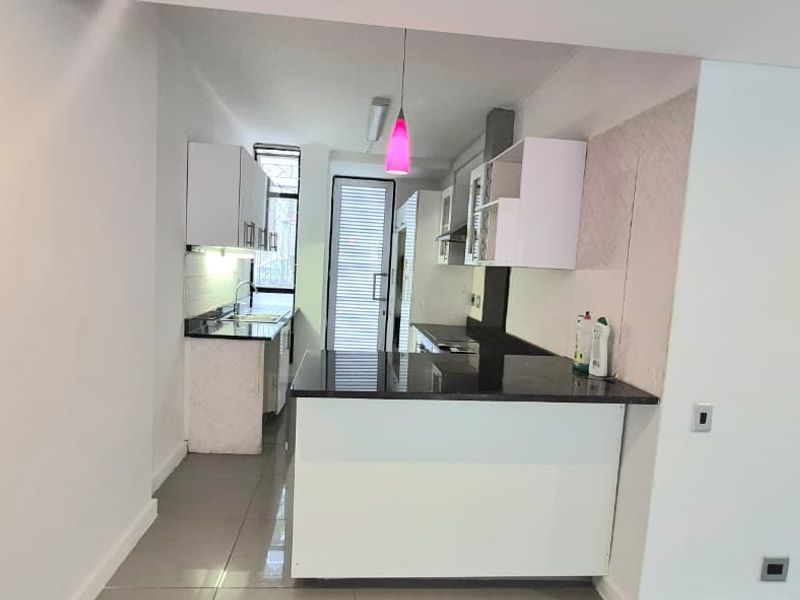 A clean, modern kitchen featuring granite countertops, white cabinetry, and tiled flooring, offering a functional and bright workspace.