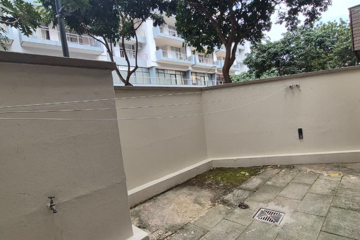 A private rear courtyard area featuring paved flooring, a retractable clothesline, an external water tap, and an installed air conditioning condenser unit.