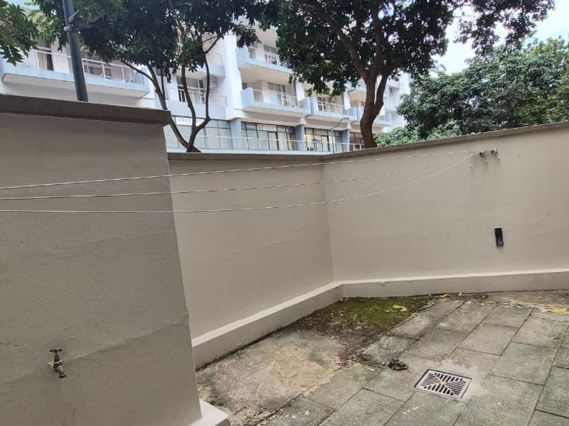 A private rear courtyard area featuring paved flooring, a retractable clothesline, an external water tap, and an installed air conditioning condenser unit.