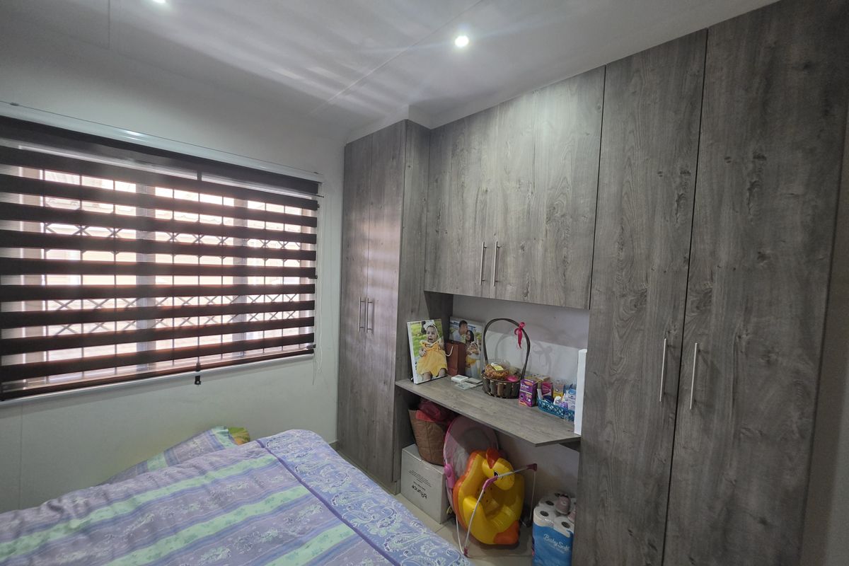 A bedroom featuring extensive built-in wooden cupboards with an integrated desk area and modern recessed ceiling lighting.