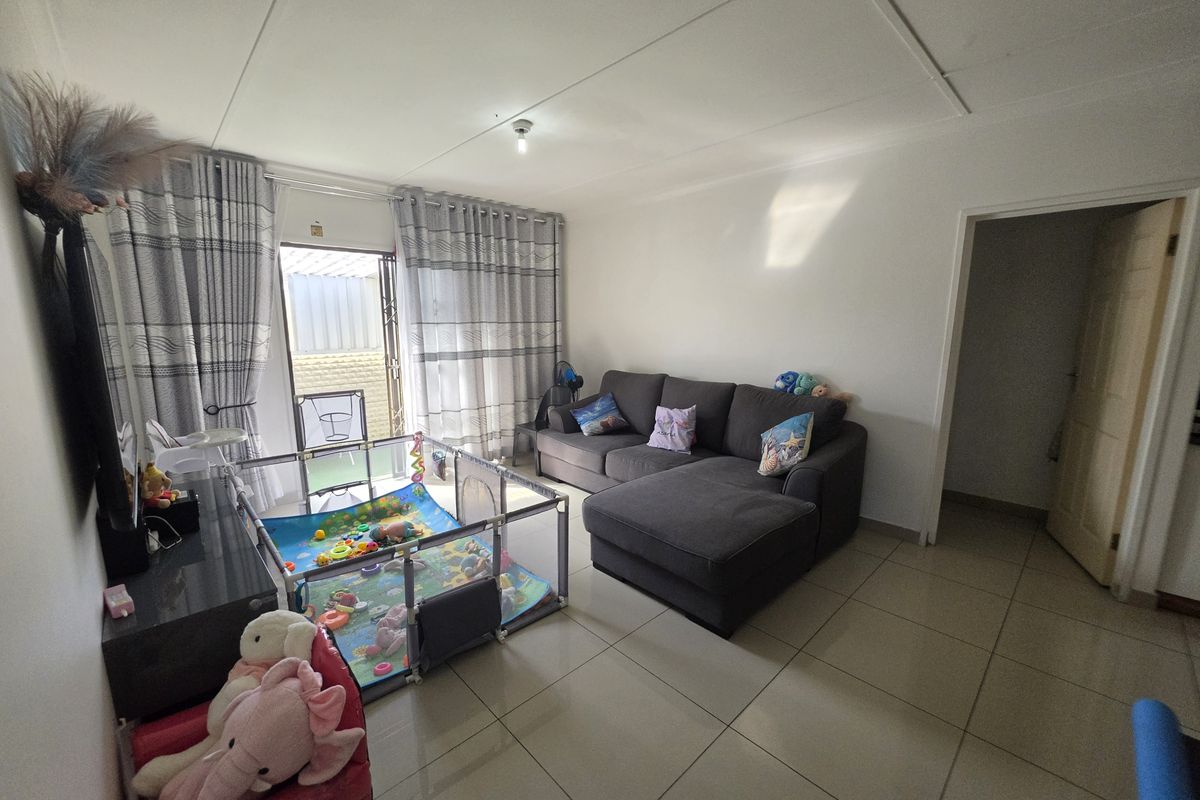A bright living room featuring large format floor tiles and a sliding glass door providing direct access to the outdoor area.