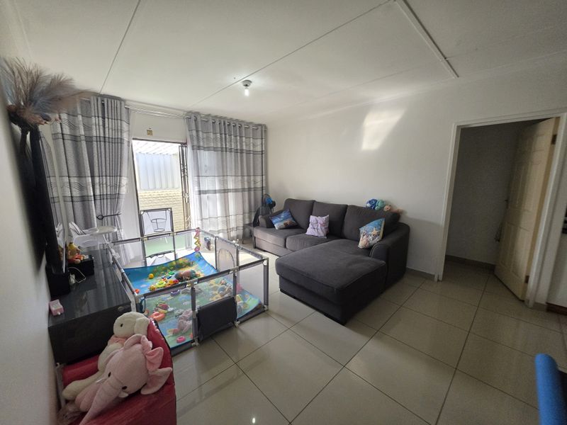 A bright living room featuring large format floor tiles and a sliding glass door providing direct access to the outdoor area.
