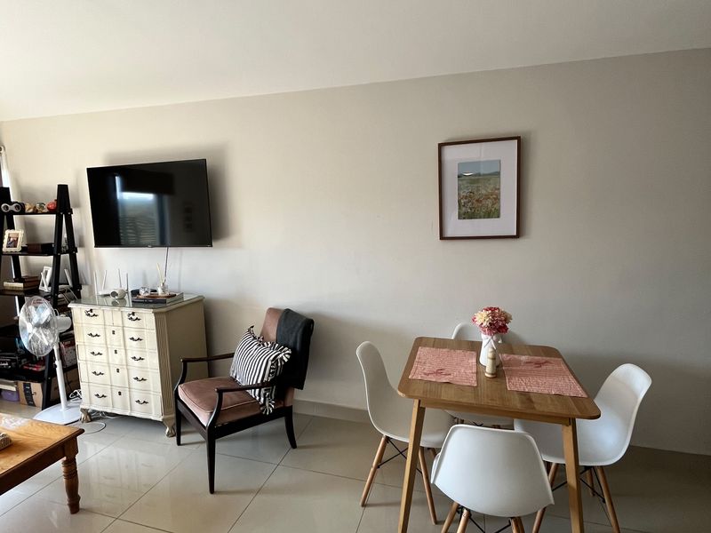 A bright living area featuring neutral tiled flooring and a wall-mounted television, providing a functional and open space for relaxation.