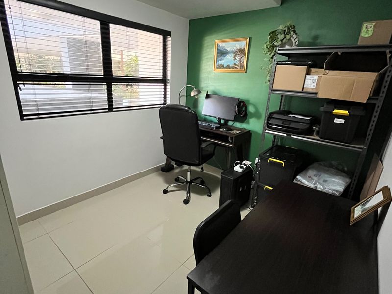A functional home office space featuring tiled flooring, a large window with venetian blinds, and a dedicated workspace area.