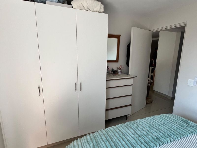 A bedroom featuring a white built-in wardrobe and tiled flooring, providing functional storage space within the apartment.