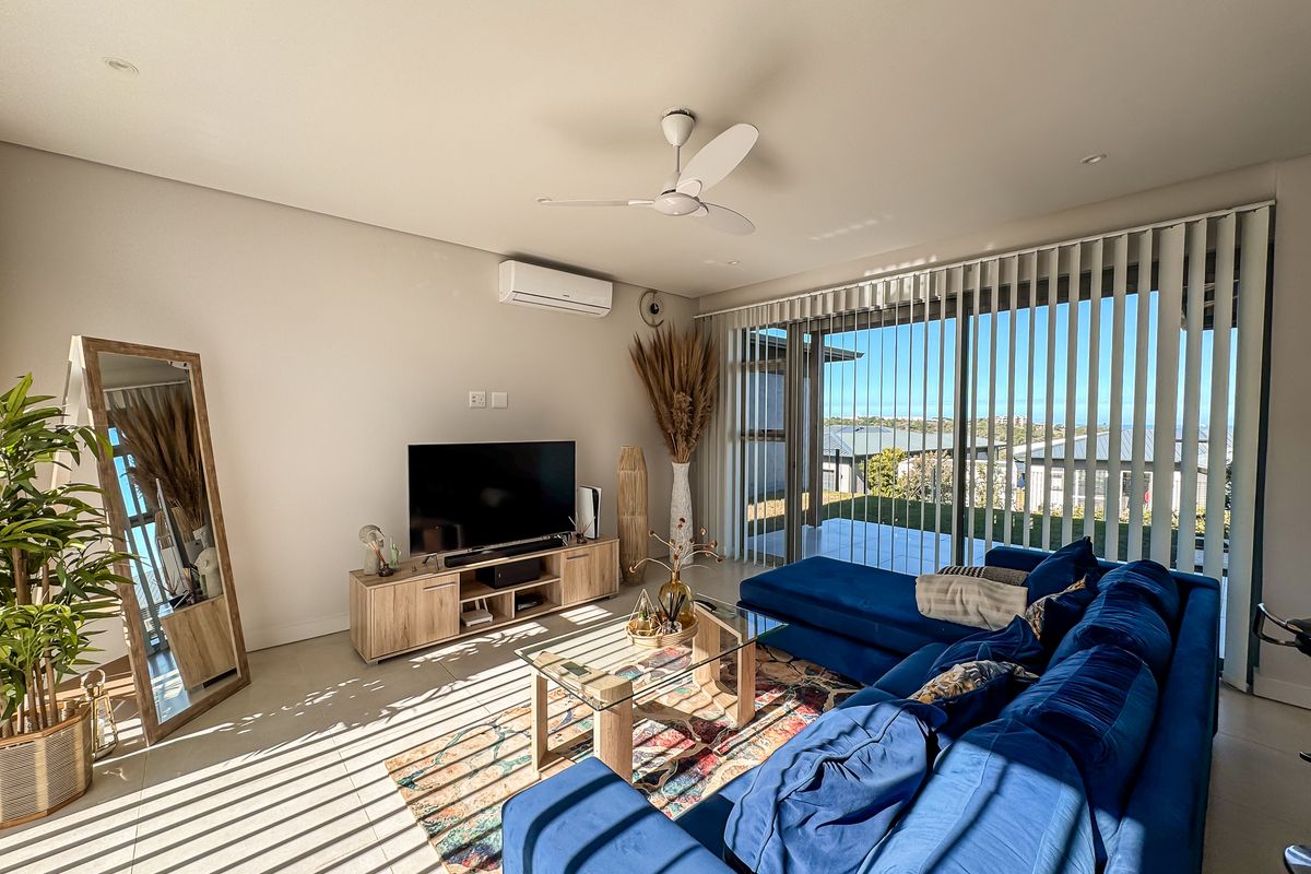 Bright and modern living room featuring tiled flooring, a ceiling fan, split-system air conditioning, and large sliding glass doors leading to an outdoor area.