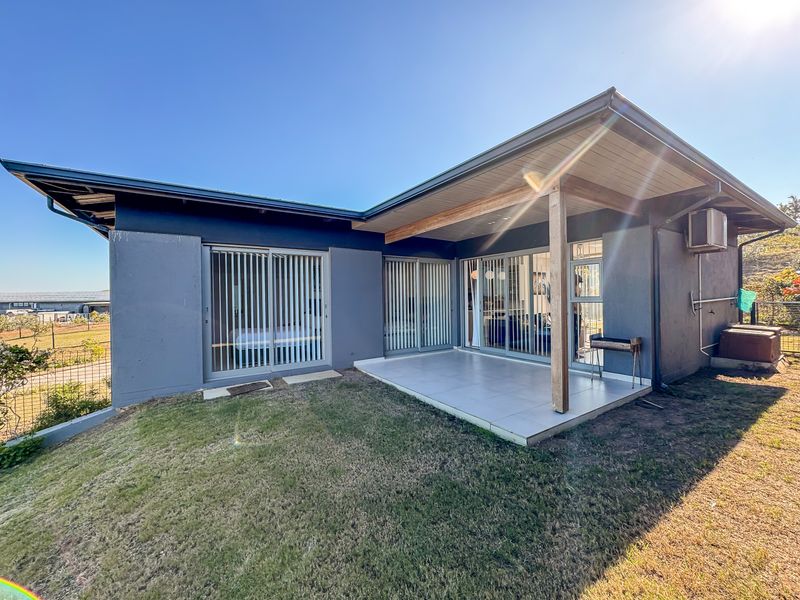 Rear exterior view of the townhouse featuring a covered tiled patio, sliding glass doors, and a well-maintained facade.