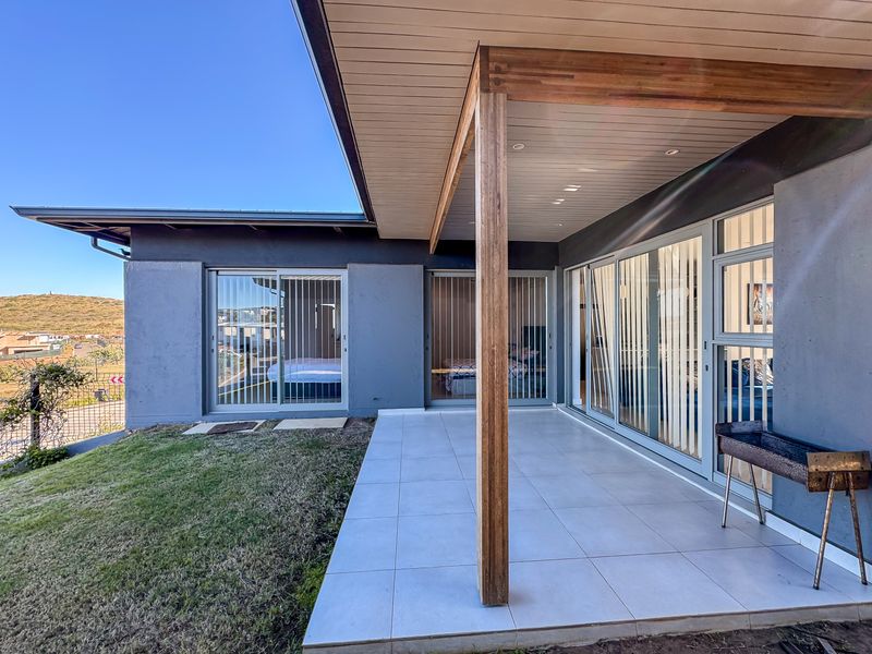 A modern covered patio featuring tiled flooring, timber ceiling accents, and large sliding glass doors providing seamless indoor-outdoor flow.