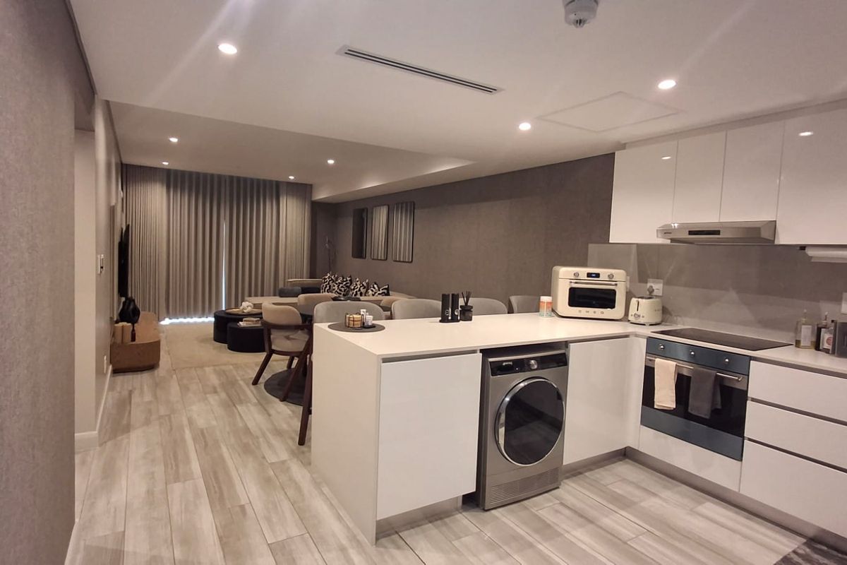Modern open-plan living area featuring a sleek kitchen with integrated appliances, stone countertops, and contemporary finishes, seamlessly flowing into the lounge space.