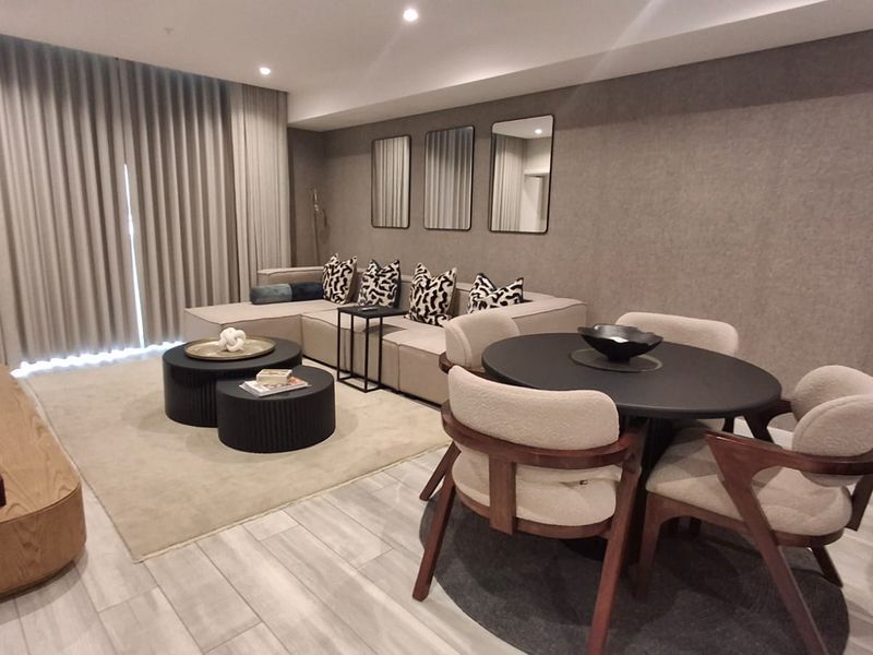 A modern open-plan living and dining area featuring neutral tones, tiled flooring, recessed lighting, and floor-to-ceiling curtains.