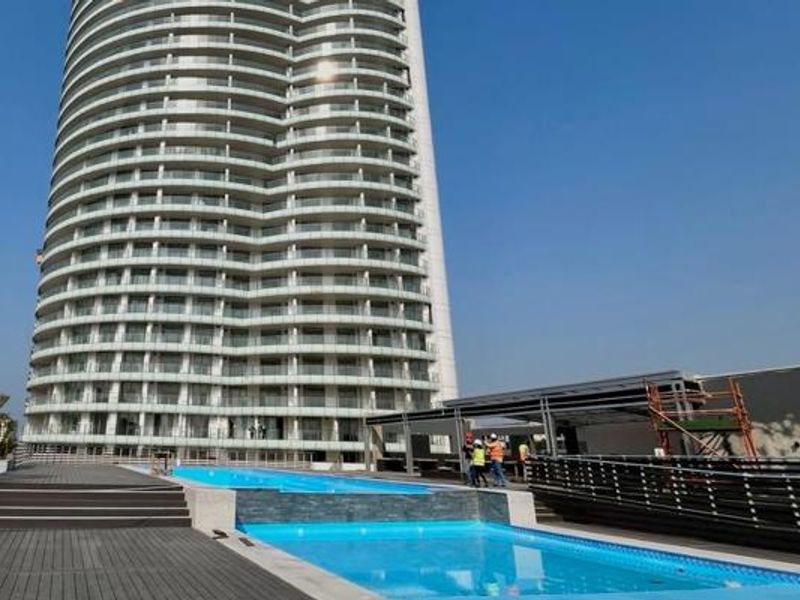 Modern high-rise apartment building featuring a swimming pool and timber decking area, offering a contemporary outdoor lifestyle space.