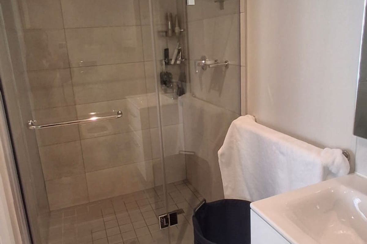 Modern bathroom featuring a glass-enclosed shower with tiled walls and a sleek white vanity cabinet with an integrated sink.