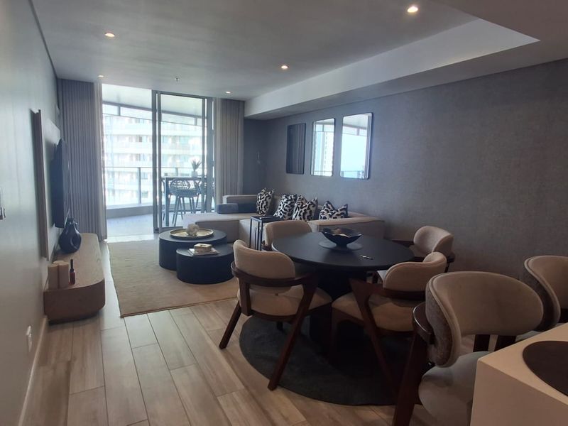 Spacious open-plan living and dining area featuring modern tiled flooring, recessed lighting, and large sliding doors leading to a private balcony.