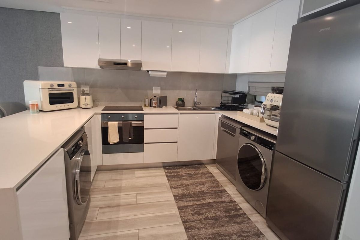 Modern kitchen featuring sleek white cabinetry, stone countertops, integrated appliances, and high-quality finishes in a clean, contemporary layout.