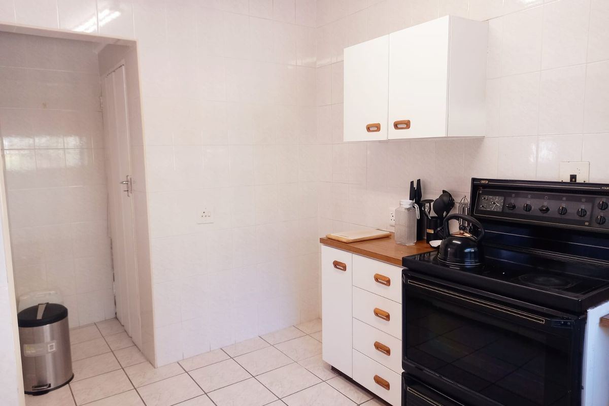 A functional kitchen featuring white cabinetry, tiled walls, and a black freestanding stove, offering a clean and practical workspace.