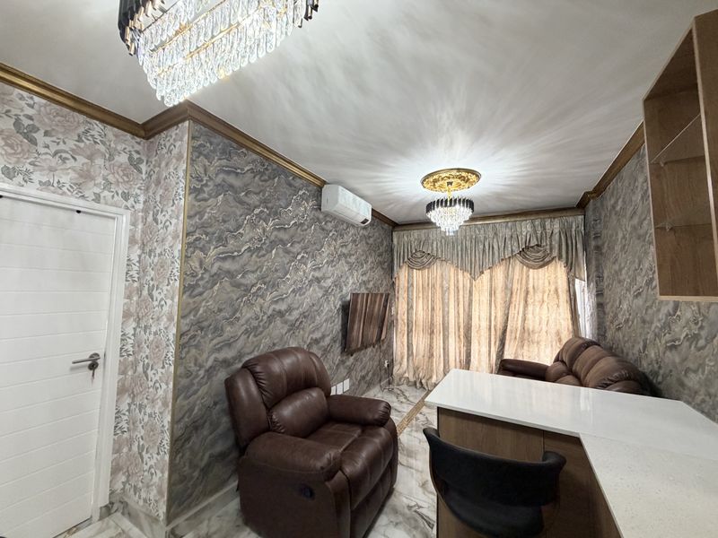 A well-appointed living room featuring marble-effect flooring, decorative crystal chandeliers, ornate ceiling roses, and a wall-mounted split-system air conditioner.