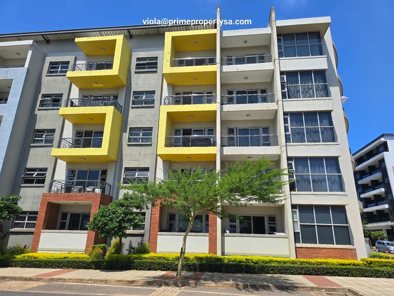 Front elevation of a multi-story apartment complex featuring yellow-accented balconies, large windows, and brick detailing.