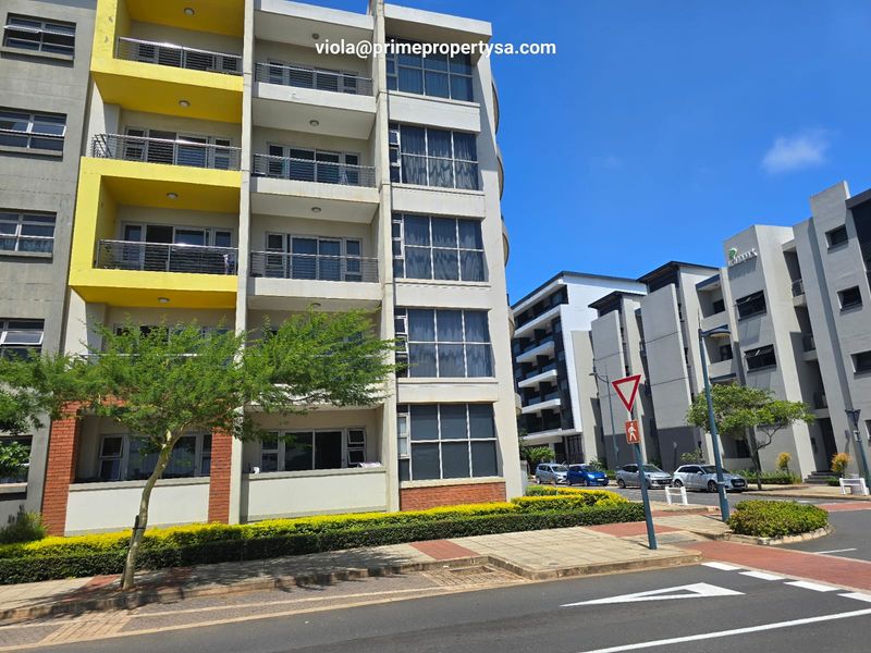 Exterior view of a modern multi-story apartment complex featuring balconies, large windows, and well-maintained surrounding landscaping.