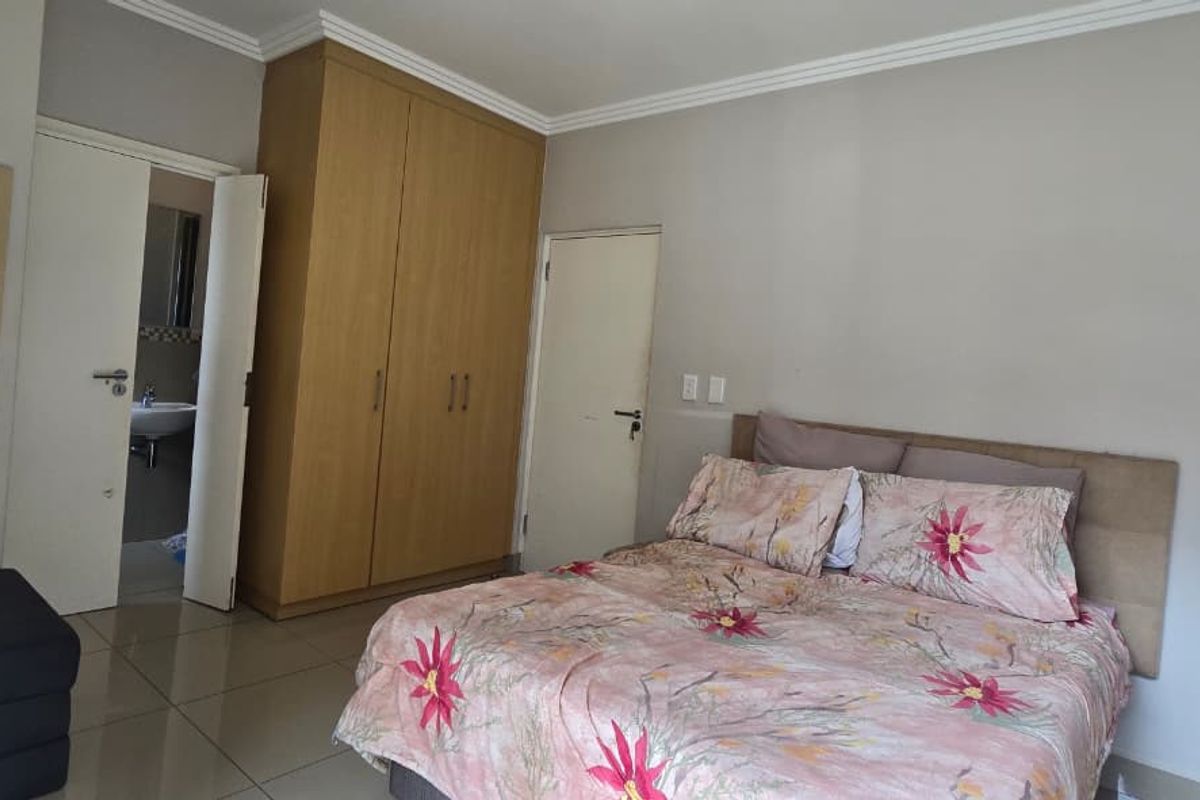 A bedroom featuring built-in cupboards, tiled flooring, and direct access to an en-suite bathroom.