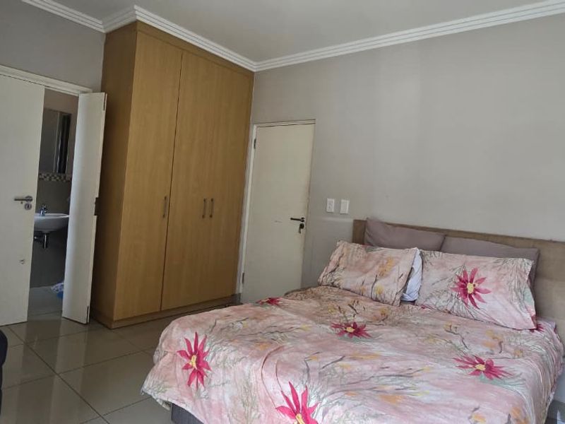 A bedroom featuring built-in cupboards, tiled flooring, and direct access to an en-suite bathroom.