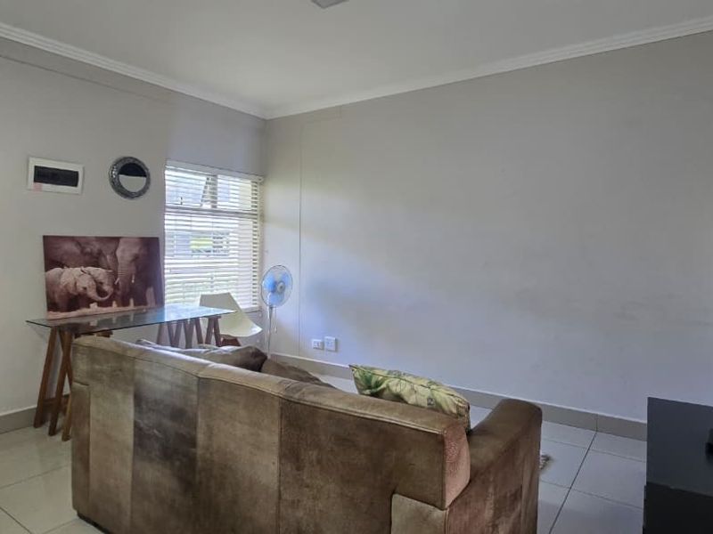 A functional living room featuring tiled flooring, neutral wall finishes, and venetian blinds, providing a clean and simple space for relaxation.