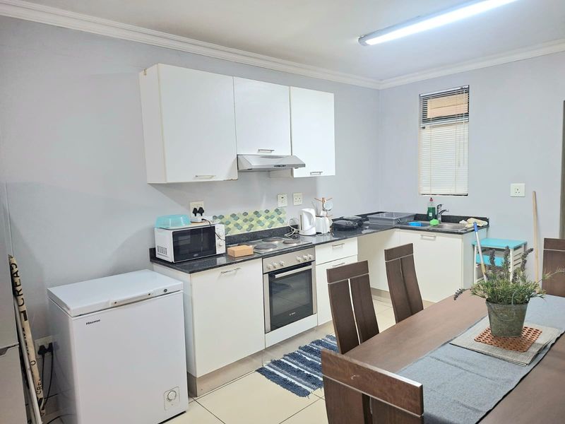 Open plan kitchen featuring white cabinetry, dark countertops, built-in oven, hob, and extractor fan, seamlessly integrated with the dining area.