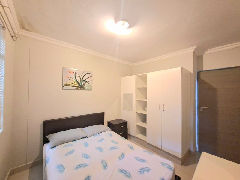 A bedroom featuring tiled flooring, coving, and a built-in wardrobe with open shelving. Note visible ceiling water staining.