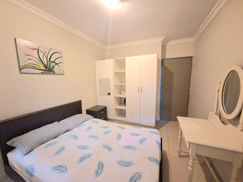 A well-maintained bedroom featuring tiled flooring, crown molding, and a functional built-in wardrobe with integrated shelving.