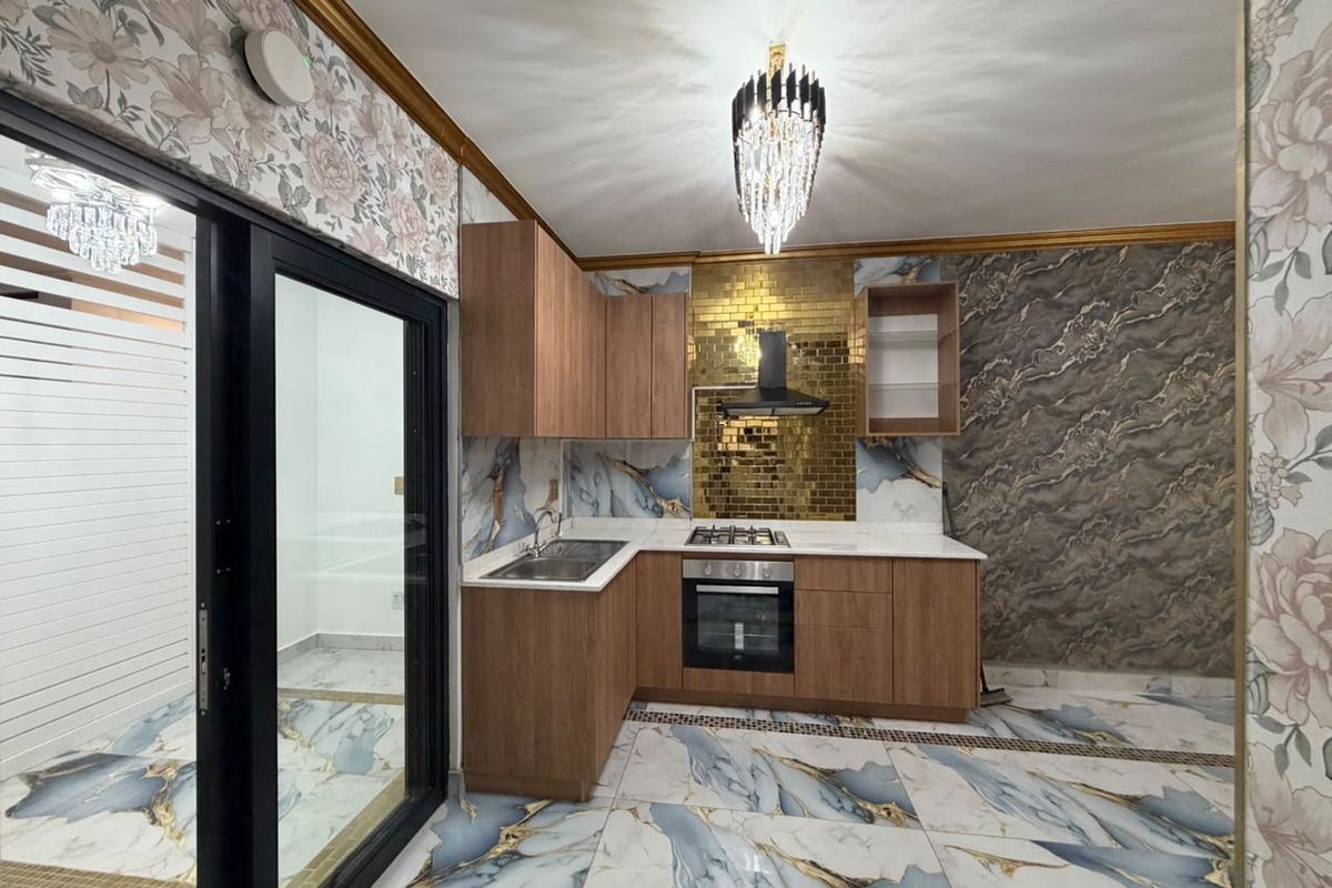 Modern kitchen featuring wood-finish cabinetry, gold-tiled backsplash, built-in oven and hob, and striking marble-patterned floor tiles.