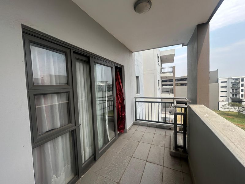 A covered balcony featuring tiled flooring, a metal balustrade, and sliding glass door access to the interior living space.