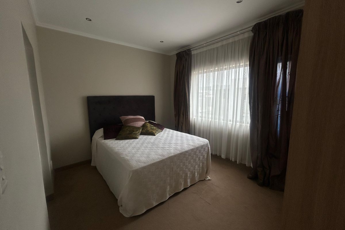 A well-maintained bedroom featuring neutral wall finishes, recessed downlighting, and fitted carpeting, providing a comfortable and functional living space.