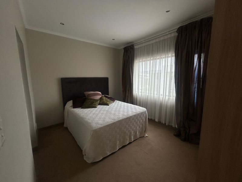 A well-maintained bedroom featuring neutral wall finishes, recessed downlighting, and fitted carpeting, providing a comfortable and functional living space.