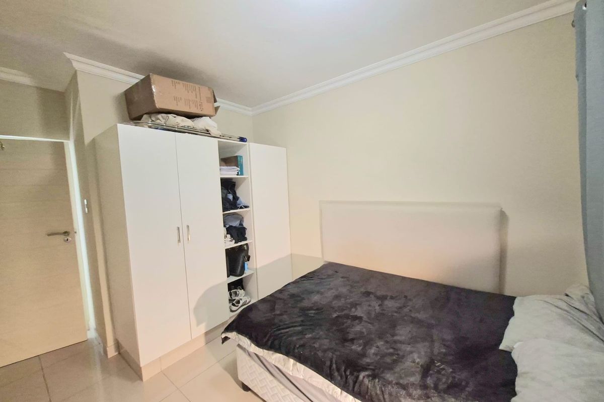 A functional bedroom featuring tiled flooring, cove cornice detailing, and a built-in wardrobe providing ample storage space.