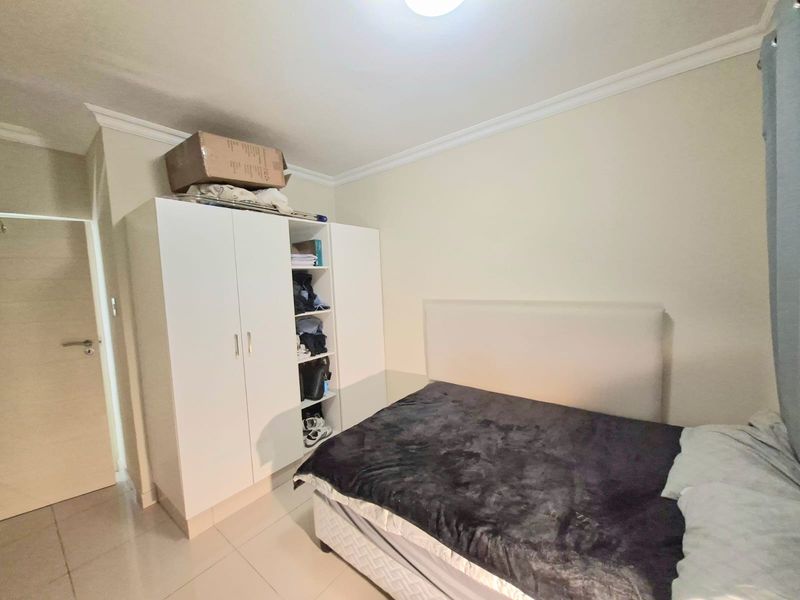 A functional bedroom featuring tiled flooring, cove cornice detailing, and a built-in wardrobe providing ample storage space.